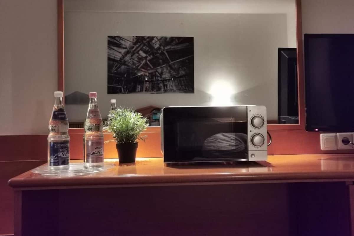 A microwave on a wooden counter with two water bottles and a small potted plant.