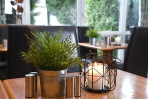 Et spisebord med en potteplante, saltkar og et lys i en lanterne.
