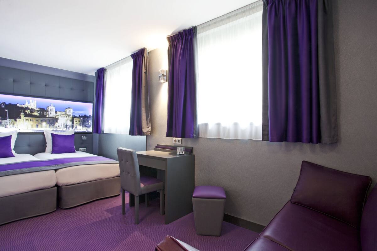 Une chambre d’hôtel équipée d’un lit, d’un bureau, d’une chaise et offrant une vue sur le paysage urbain.