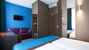 Une chambre d’hôtel comprenant un lit, un canapé, un bureau, une armoire et un téléviseur.
