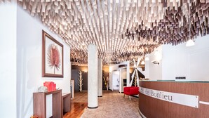 A reception area with a wooden reception desk labeled "Hotel de Bonlieu," a large framed artwork on the wall, and a patterned carpet. - Hôtel de Bonlieu (Annecy)