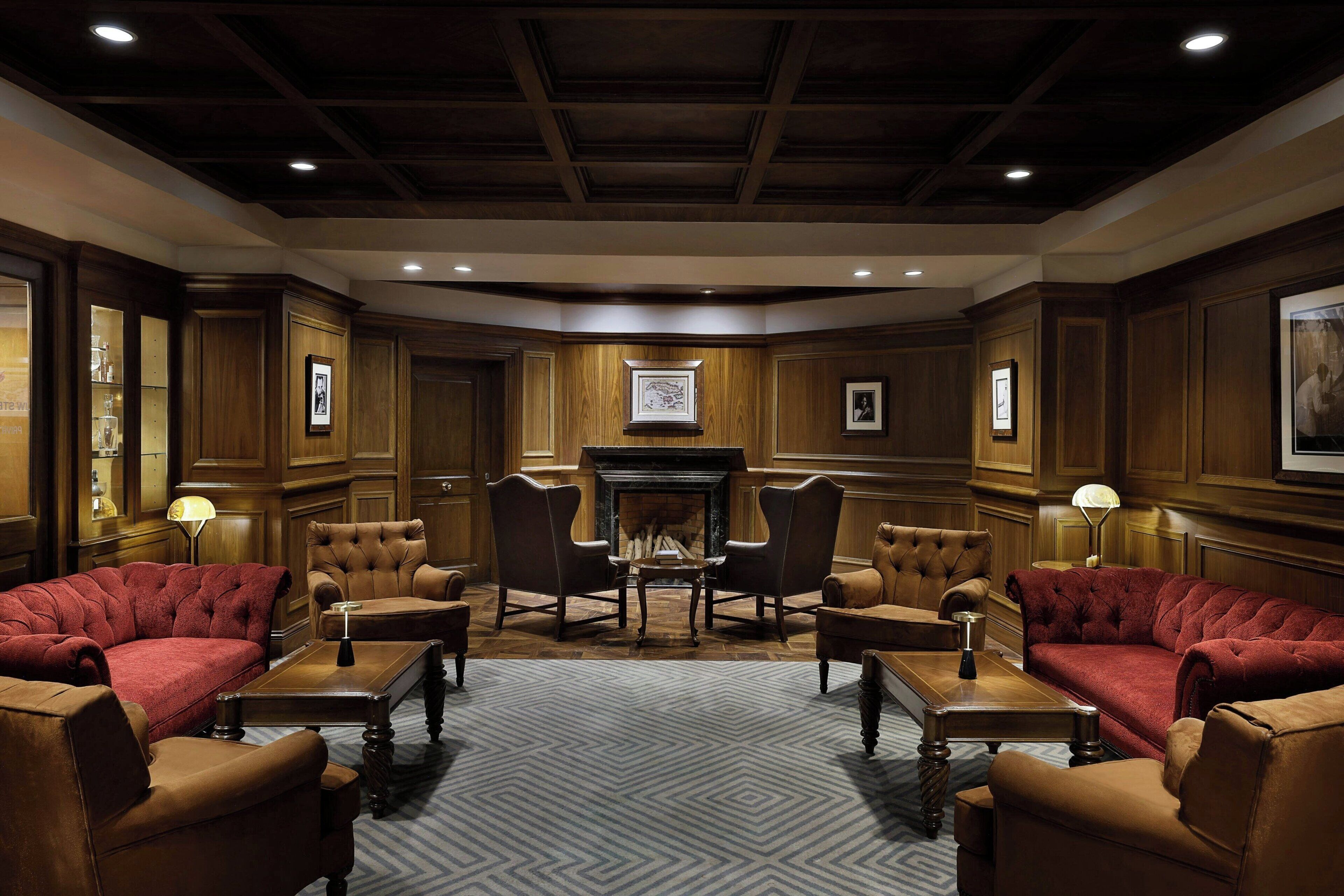 A room with a fireplace, wooden paneling, and leather furniture.