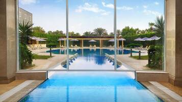 Una piscina techada, una piscina al aire libre, sombrillas