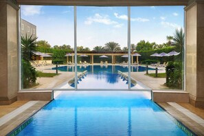 Una piscina techada, una piscina al aire libre, sombrillas