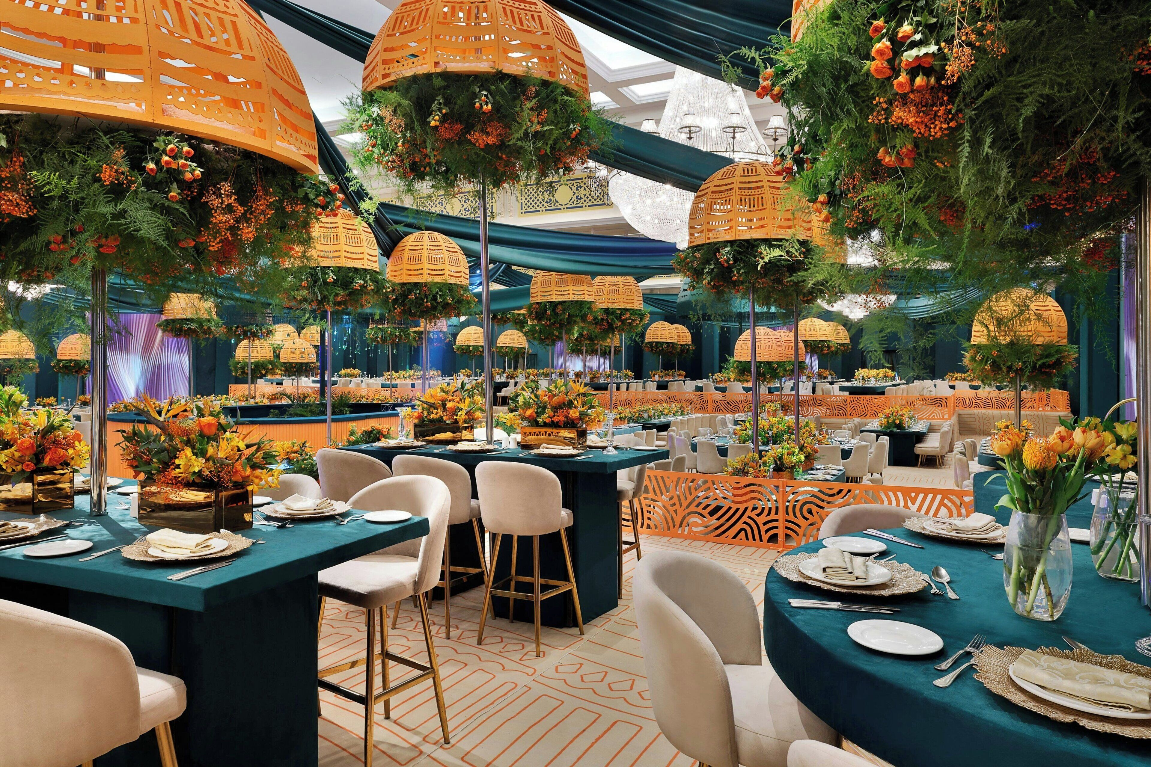 A banquet hall with round tables, chairs, and hanging lanterns.