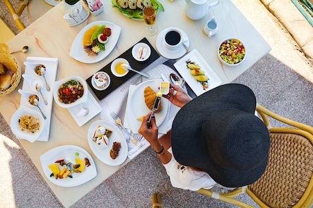 A dining table with various dishes, a coffee cup, and a person holding a napkin.