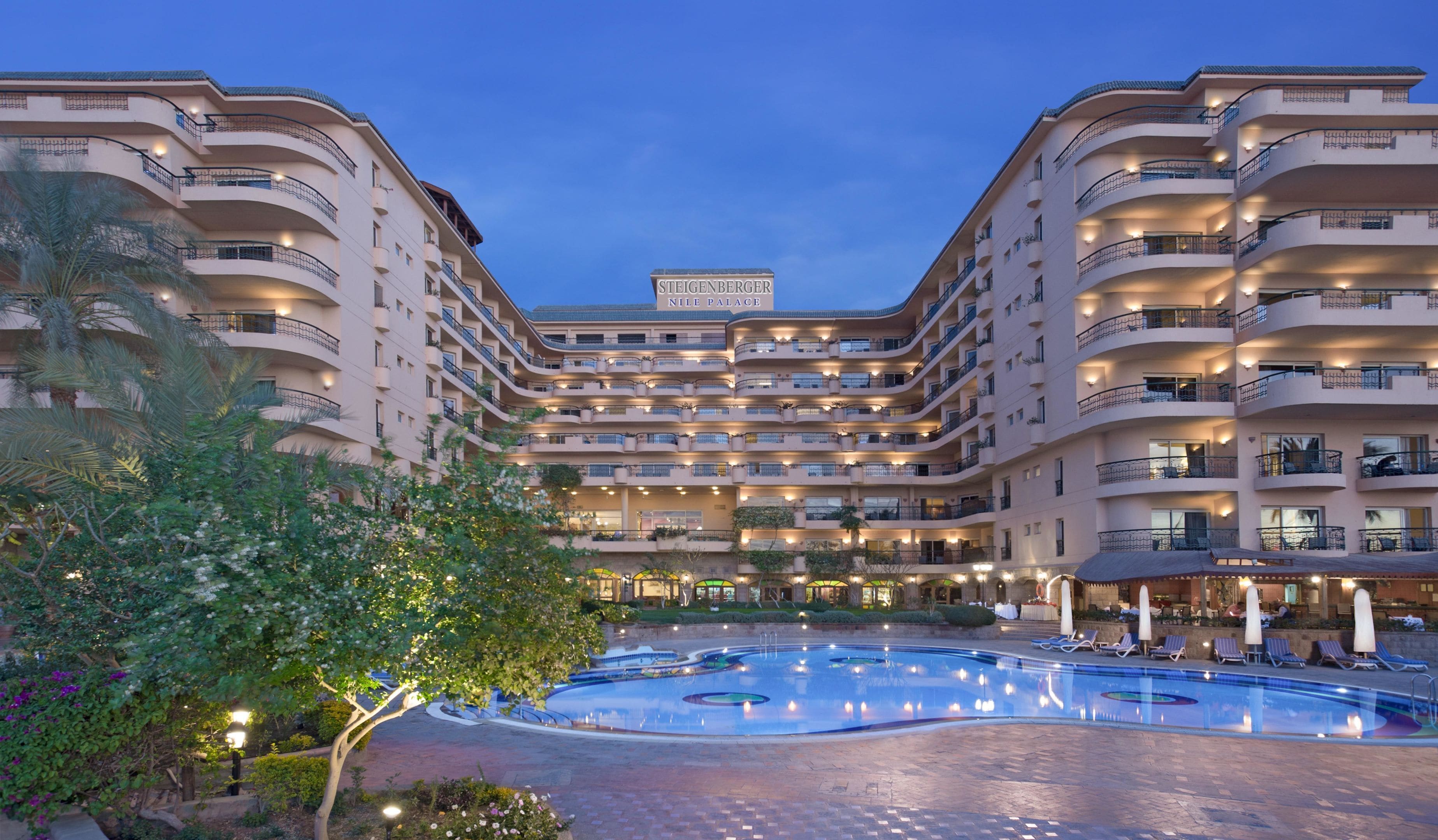 Un grand hôtel doté de nombreux balcons, d’une cour intérieure avec une piscine et d’une enseigne indiquant « Steigenberger Nile Palace ».