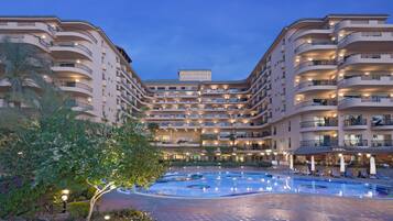 Un grand hôtel doté de nombreux balcons, d’une cour intérieure avec une piscine et d’une enseigne indiquant « Steigenberger Nile Palace ».