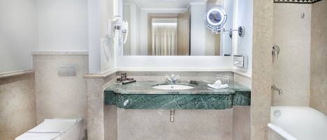 Un baño con lavamanos de mármol, inodoro y bañera.