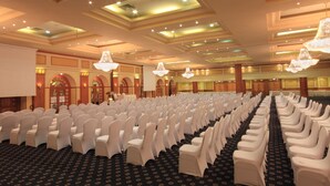 A large hall with rows of white chairs and tables, a patterned carpet, and chandeliers. - Steigenberger Nile Palace (Luxor)