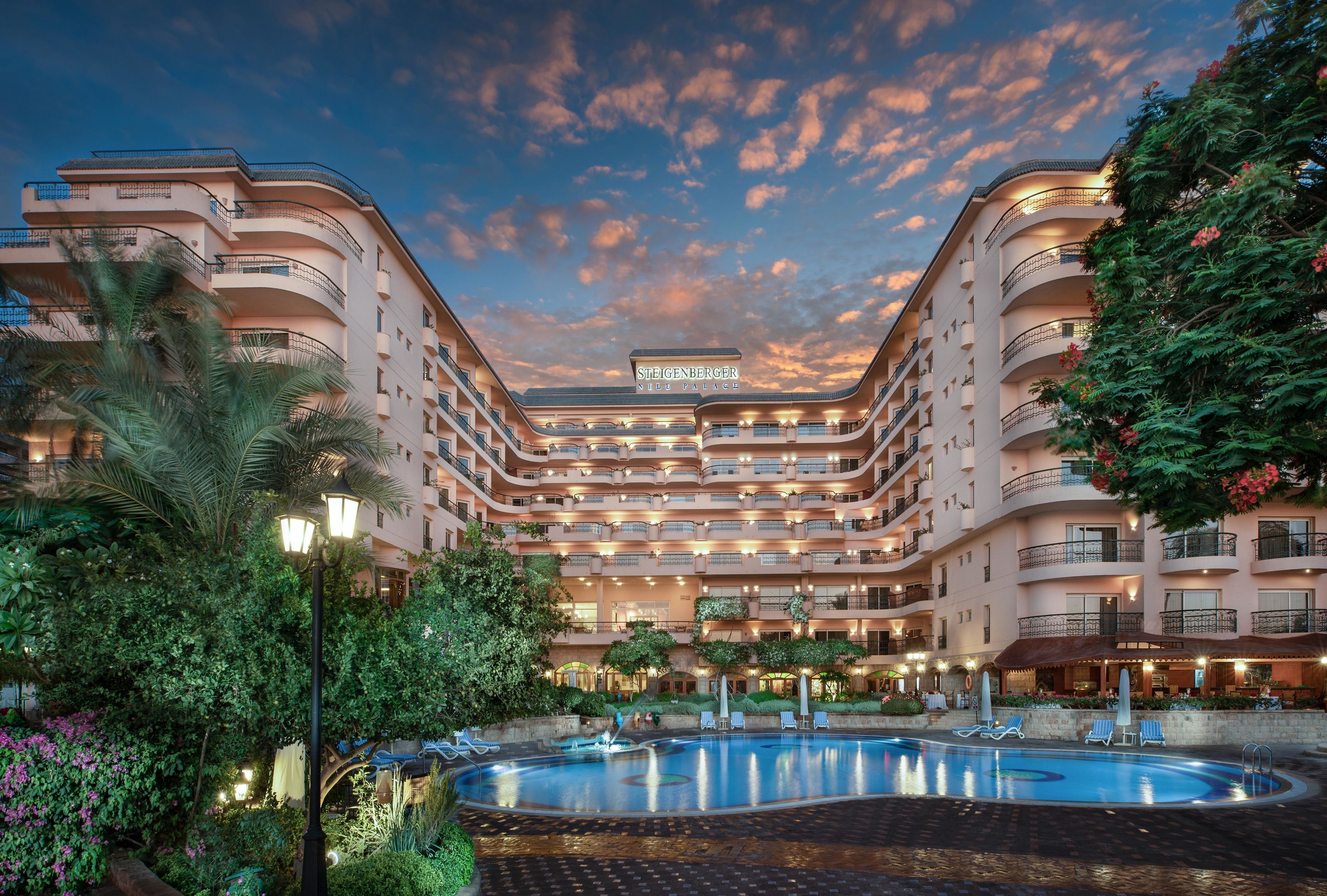 Ein mehrstöckiges Hotel mit Pool, Balkonen und üppigem Grün.