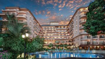 Ein mehrstöckiges Hotel mit Pool, Balkonen und üppigem Grün.