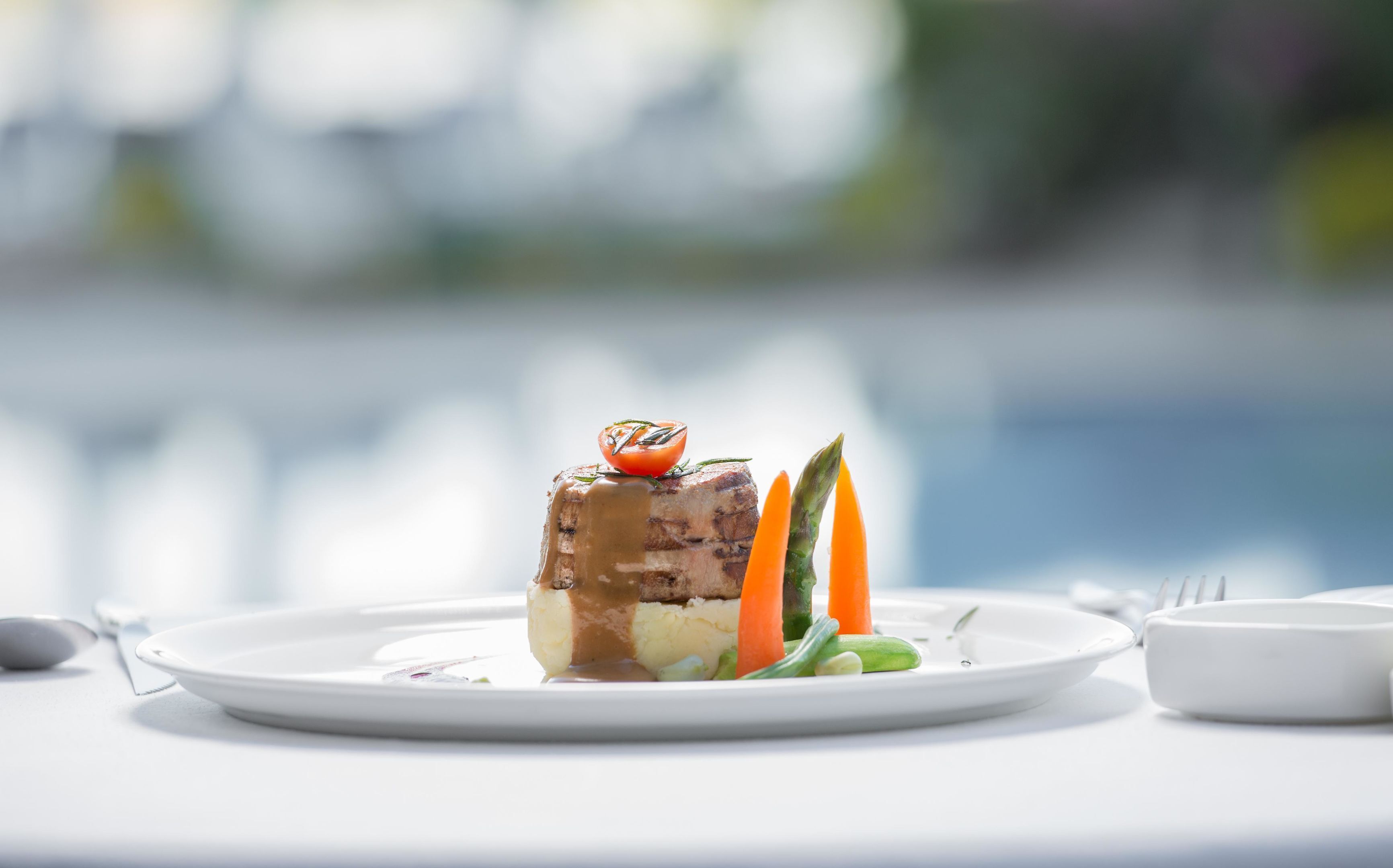 A plated dish with a piece of meat, vegetables, and a sauce.