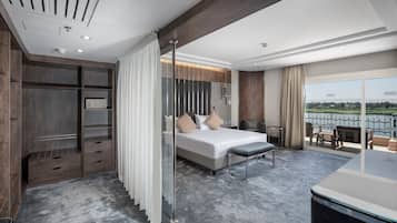 A modern hotel room with a large bed, a walk-in closet, a balcony with a view, and a dining area.