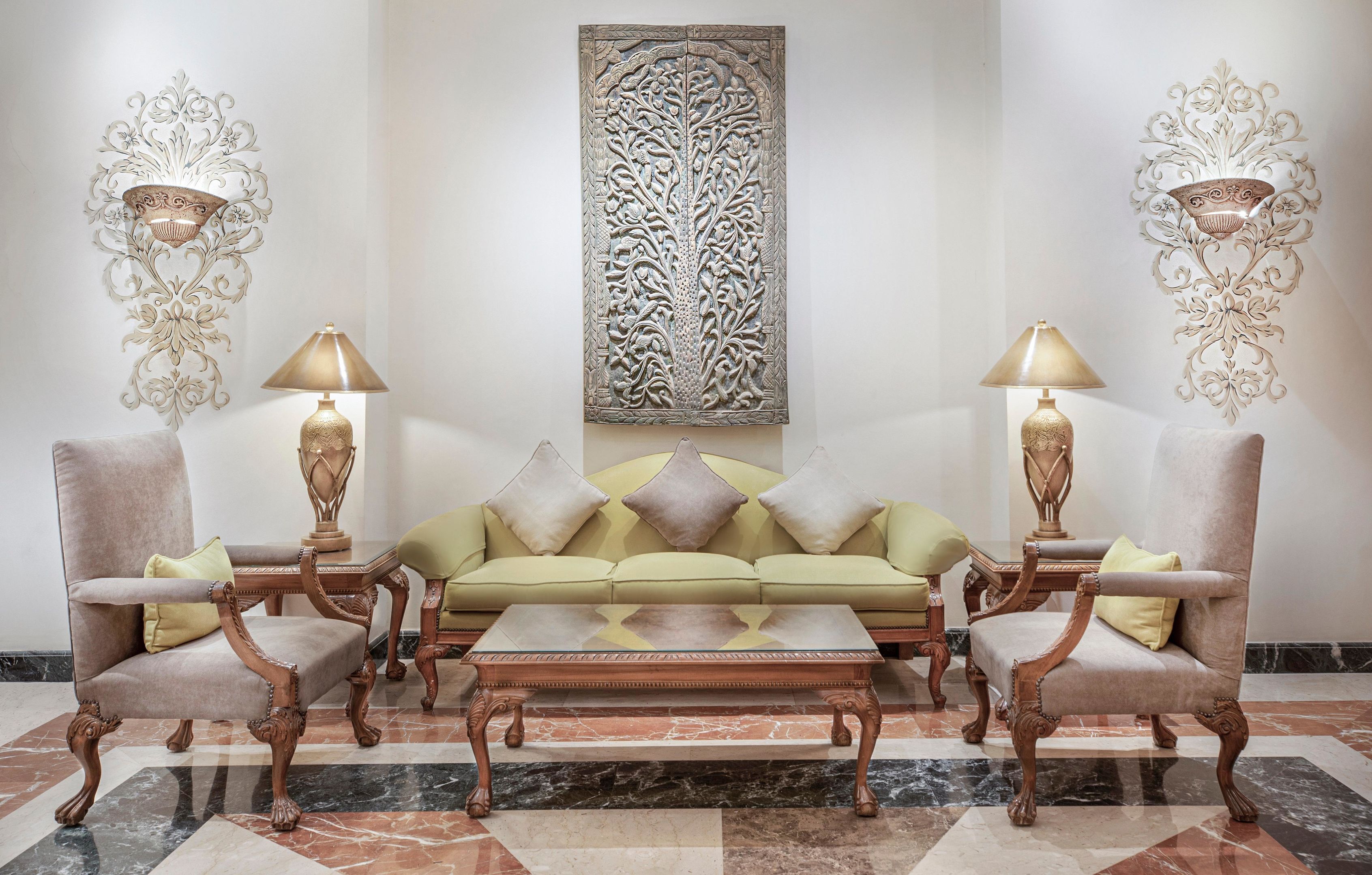 Quarto com sofá, duas poltronas, uma mesa de centro e duas luminárias de parede.