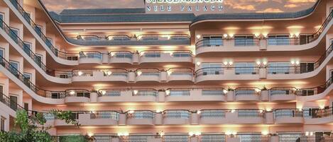 A multi-story hotel with a pool area, featuring balconies and outdoor seating.