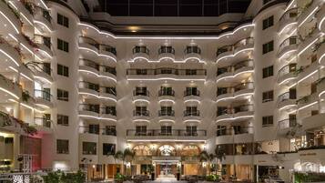 A multi-story hotel with a central courtyard, balconies on each floor, and outdoor seating areas.