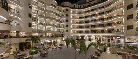 Un hotel de varios pisos con un patio central que incluye asientos al aire libre y áreas verdes.
