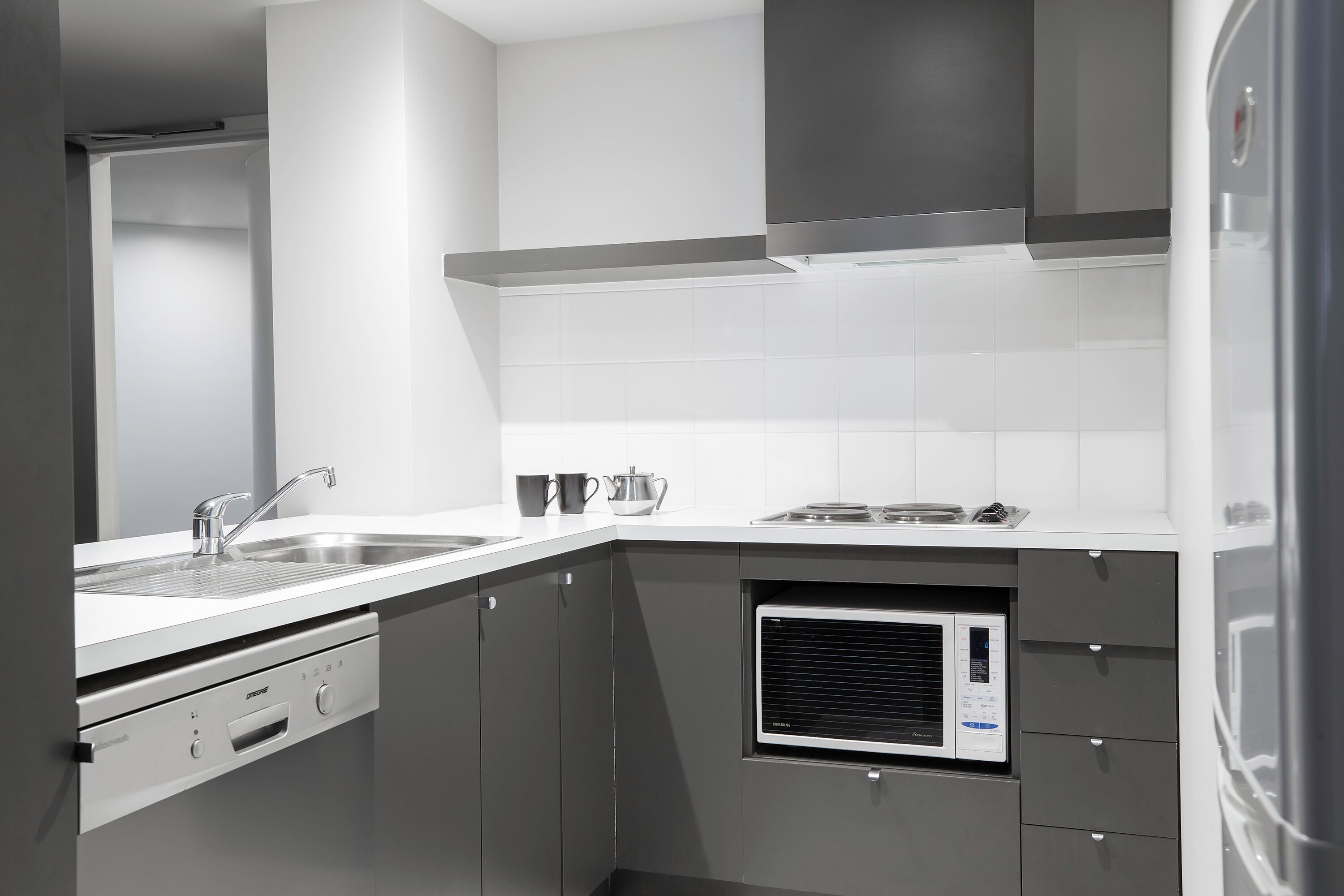 Une cuisine moderne équipée d’un four à micro-ondes encastré, d’un évier et d’une cuisinière.