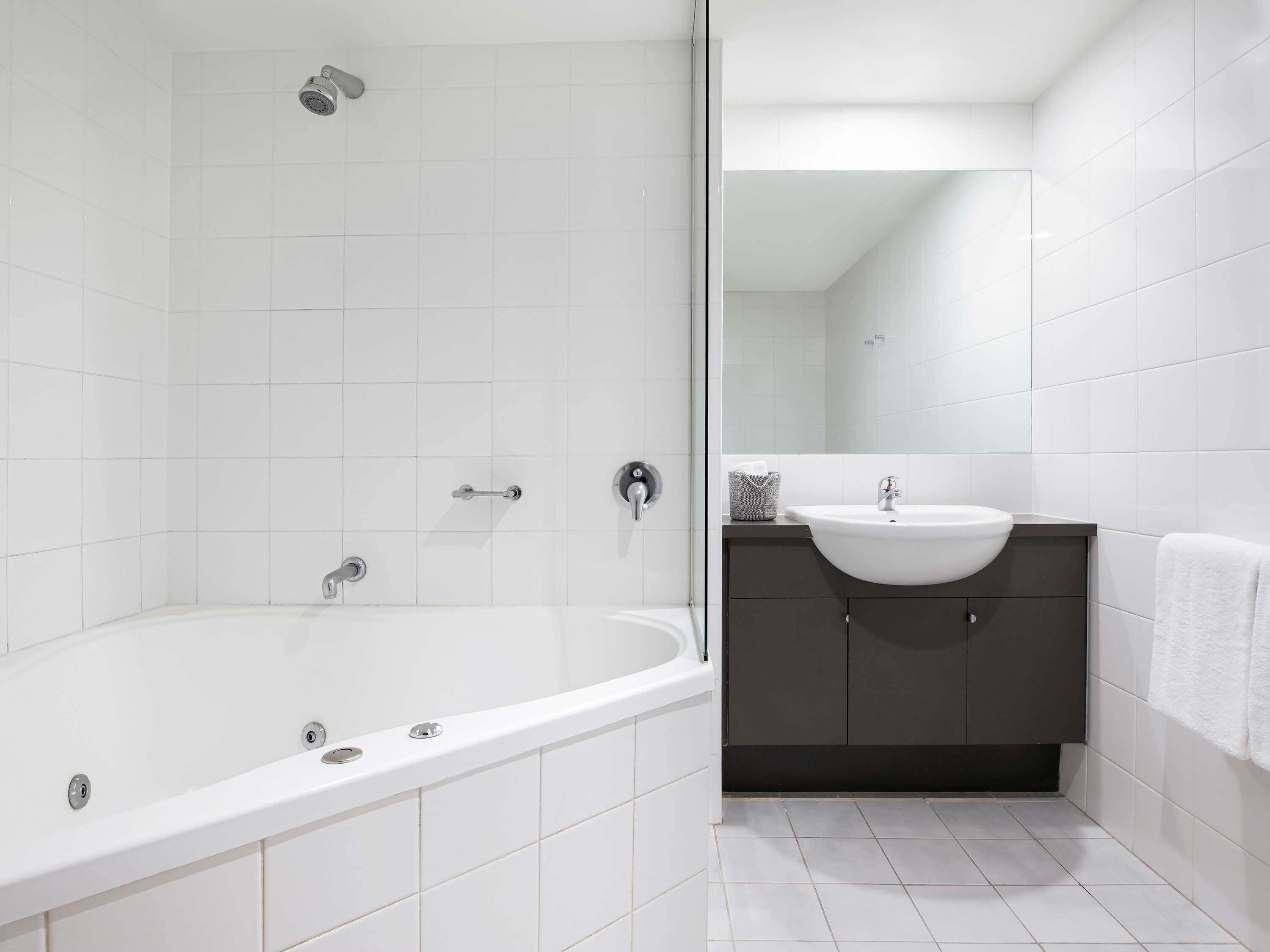 A modern bathroom with a bathtub, a sink, and a dark-toned vanity.
