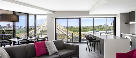 A modern living room with a sofa, a dining area, and a kitchen.