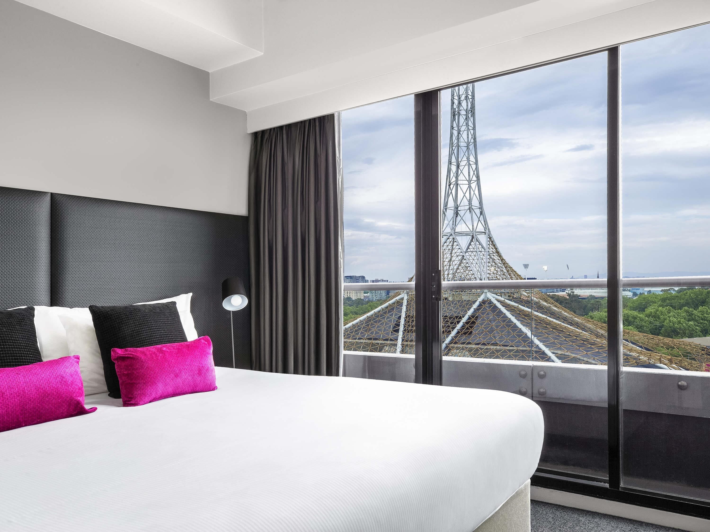 Camera d'albergo con un letto grande, vista su un ponte e arredamento moderno.