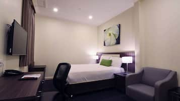 Una camera d'albergo con un letto, una scrivania, una sedia, una televisione e un quadro appeso al muro.