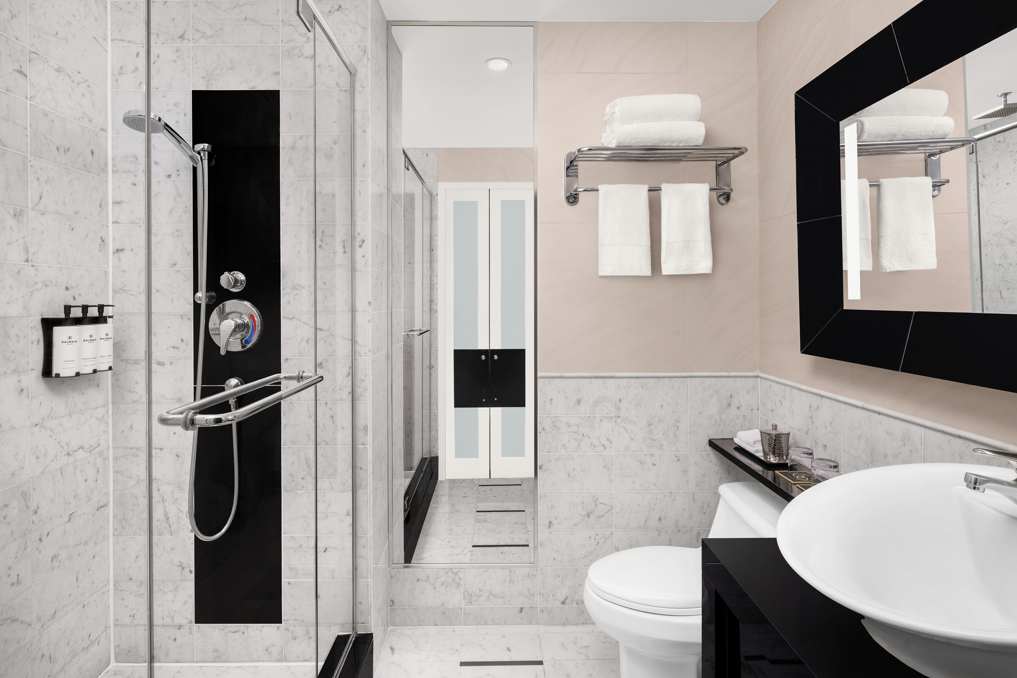 Un baño moderno con ducha a ras de suelo, inodoro, lavabo y perchero para toallas.