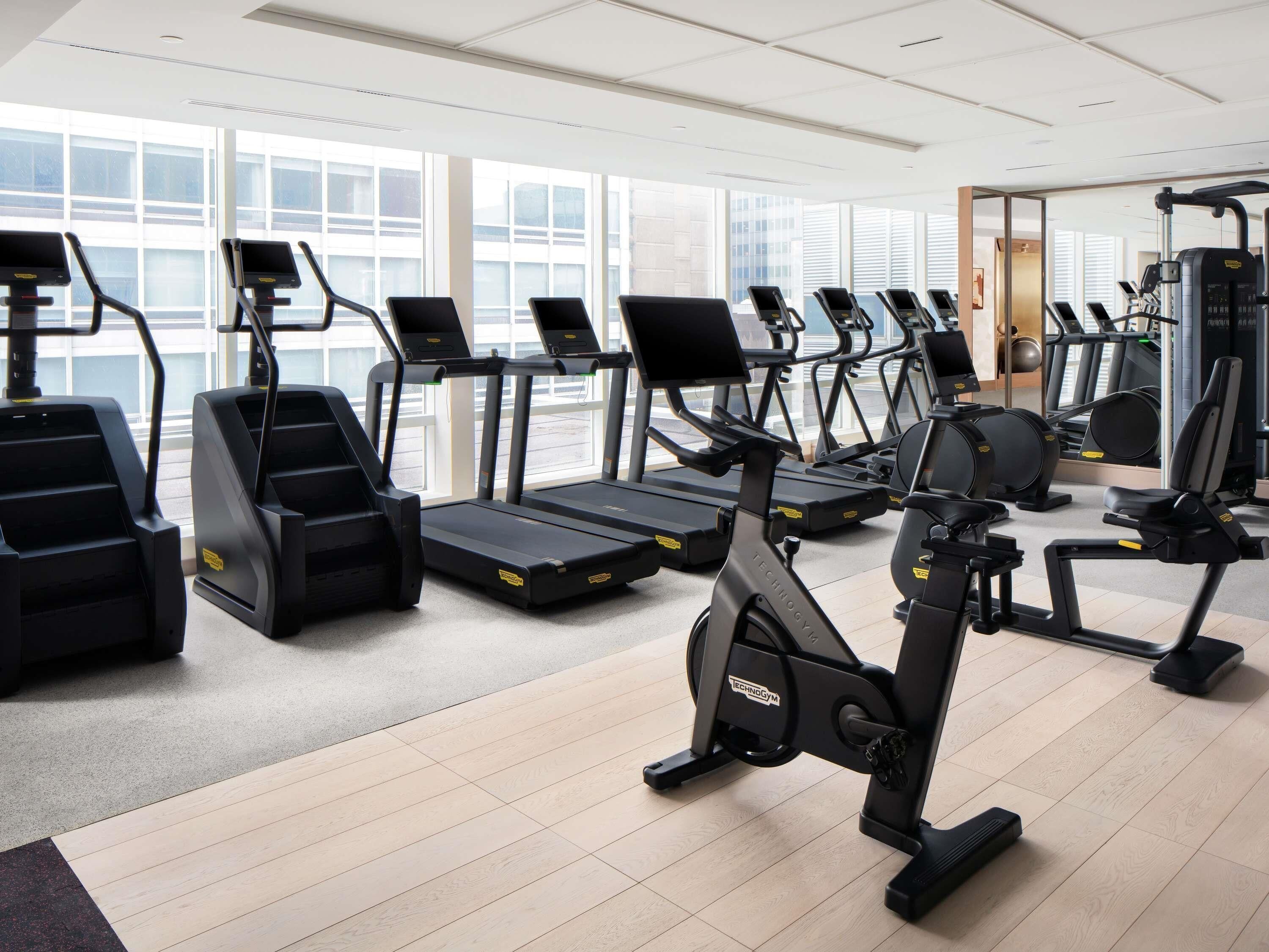 A gym with multiple treadmills, stationary bikes, and elliptical machines.