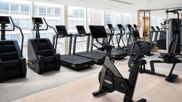 A gym with multiple treadmills, stationary bikes, and elliptical machines.