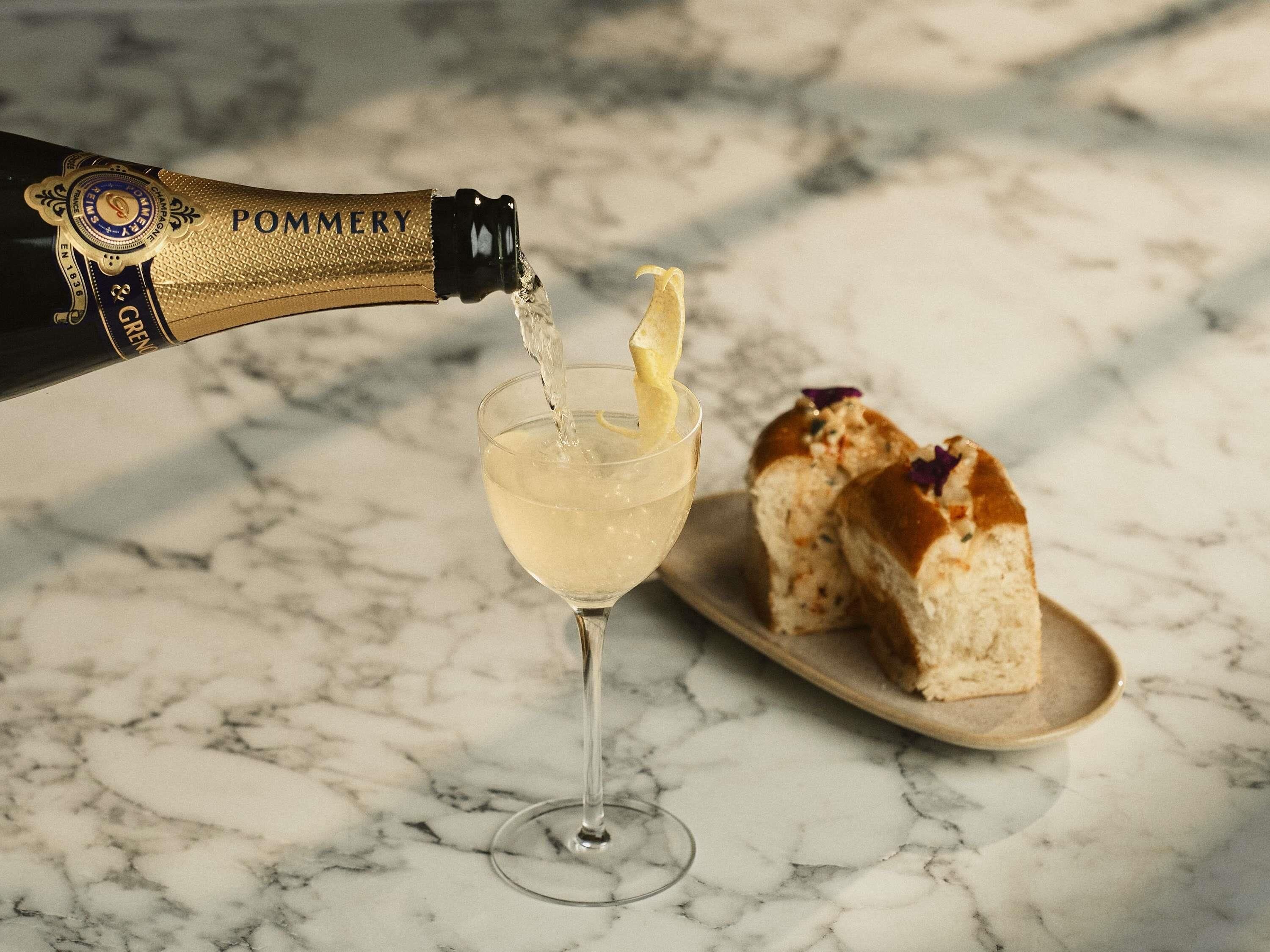 A bottle of Pommery champagne being poured into a glass.