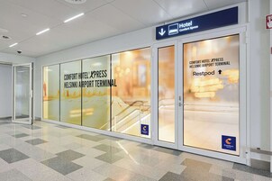 Entrada de hotel con señalización para Comfort Hotel Express en la Terminal del Aeropuerto de Helsinki, indicando un Restpod.