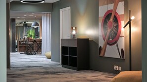 Ein Flur mit Teppichboden, einer Holzbank, einer Lampe und einer großen Uhr an der Wand.