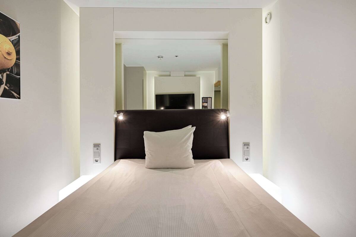 Una habitación de hotel moderna con una cama grande, un cabecero oscuro y un diseño minimalista.