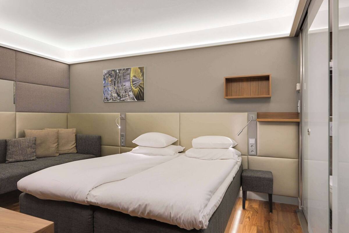 Un dormitorio moderno con una cama, un sofá, una mesita de noche y una repisa en la pared.