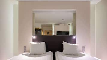 A hotel room with two single beds, a large mirror, and a door leading to a bathroom.