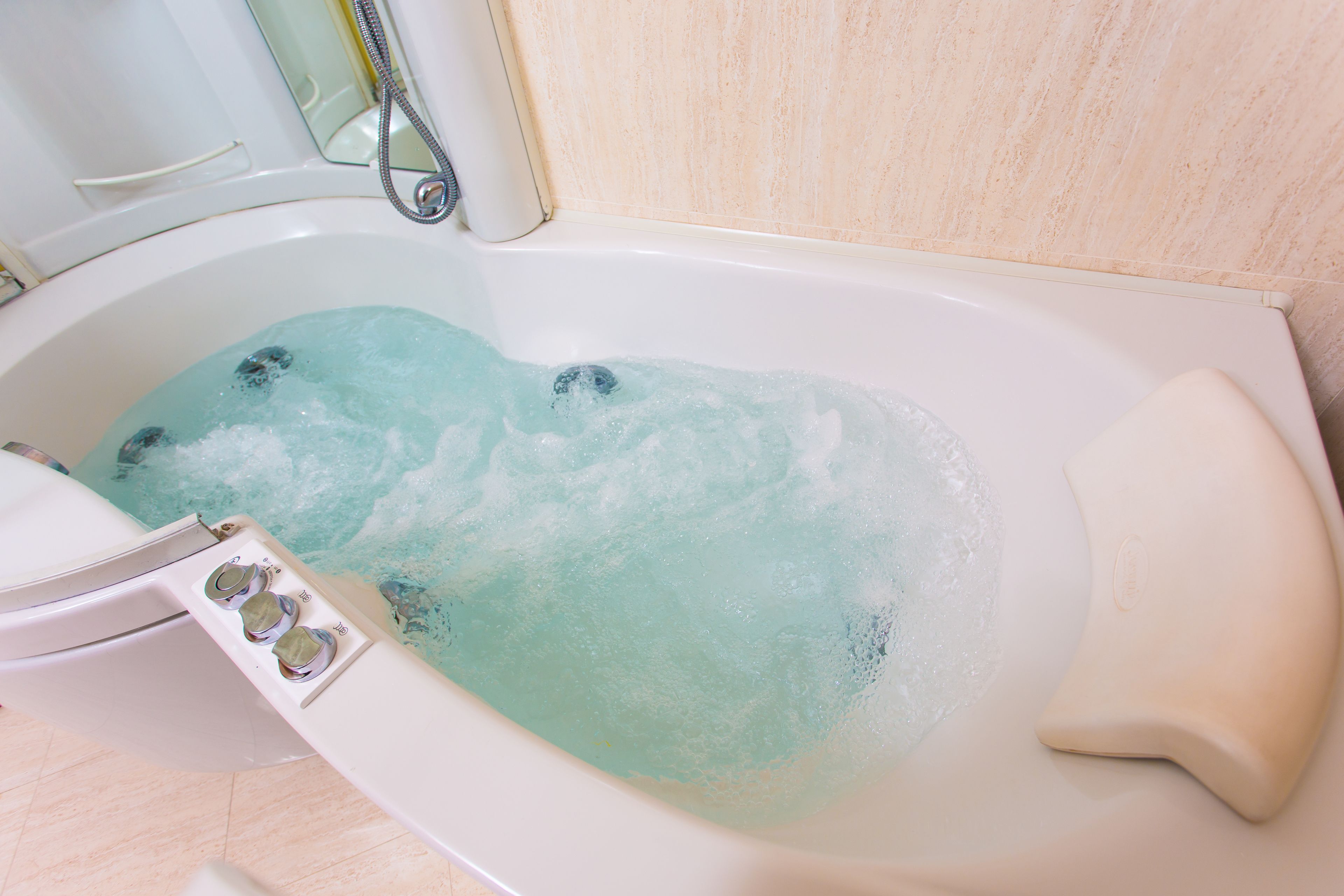 A bathtub with running water and bubbles.