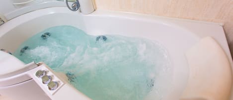A bathtub with running water and bubbles.