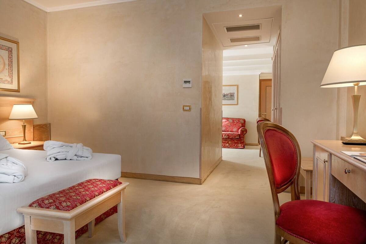 Ein Hotelzimmer mit Bett, Sitzbank, Schreibtisch und Stuhl.