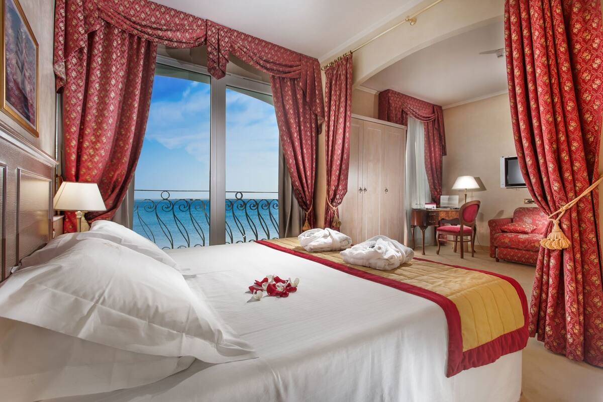 Ein Hotelzimmer mit Bett, Schreibtisch, Stuhl und Meerblick.