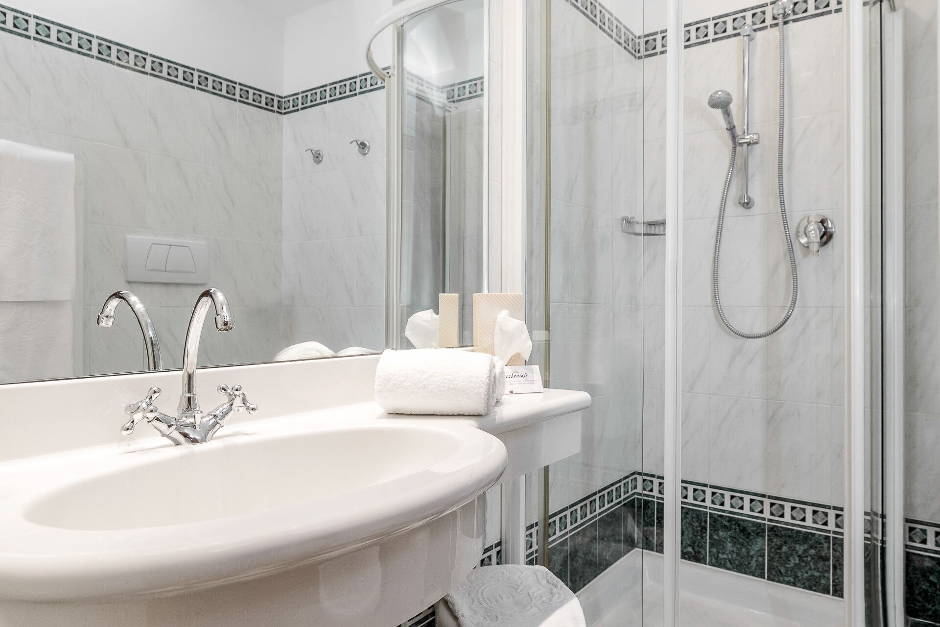A bathroom with a large white sink, a glass-enclosed shower, and a mirror.