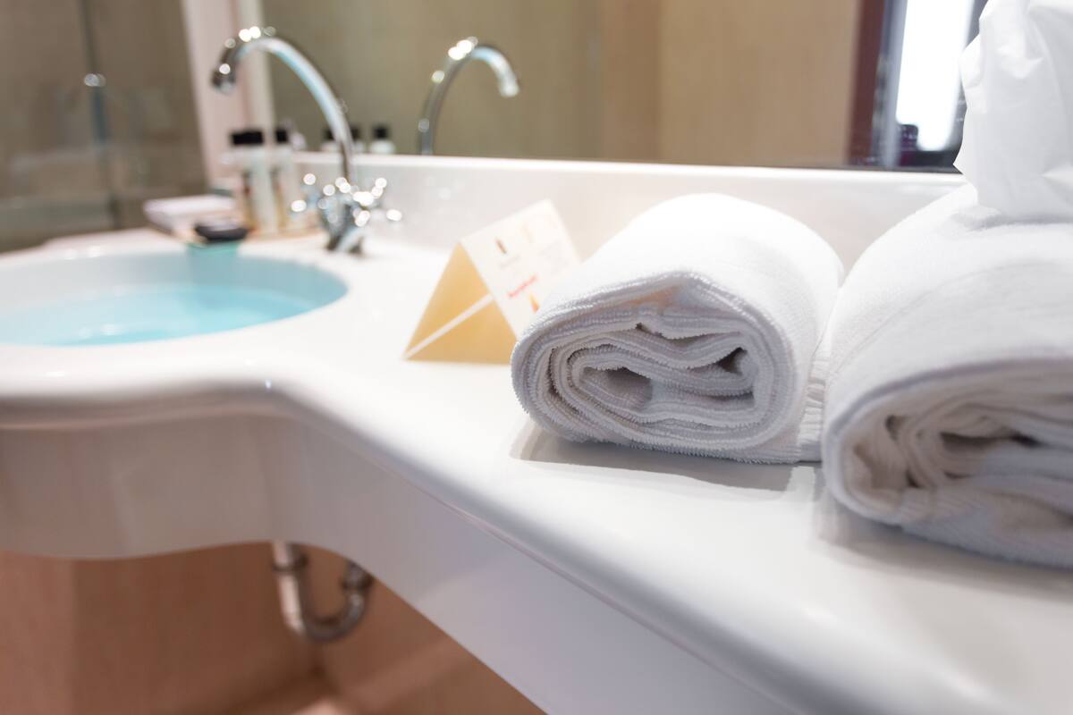 Ein Badezimmer mit Waschbecken, Spiegel und Handtüchern.