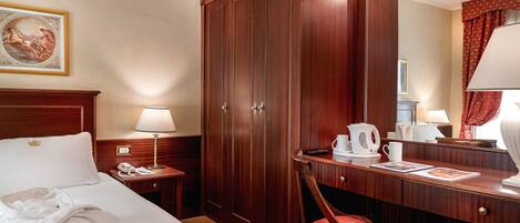 Een hotelkamer met een bed, een bureau, een stoel, een kledingkast, een spiegel en een schilderij aan de muur.