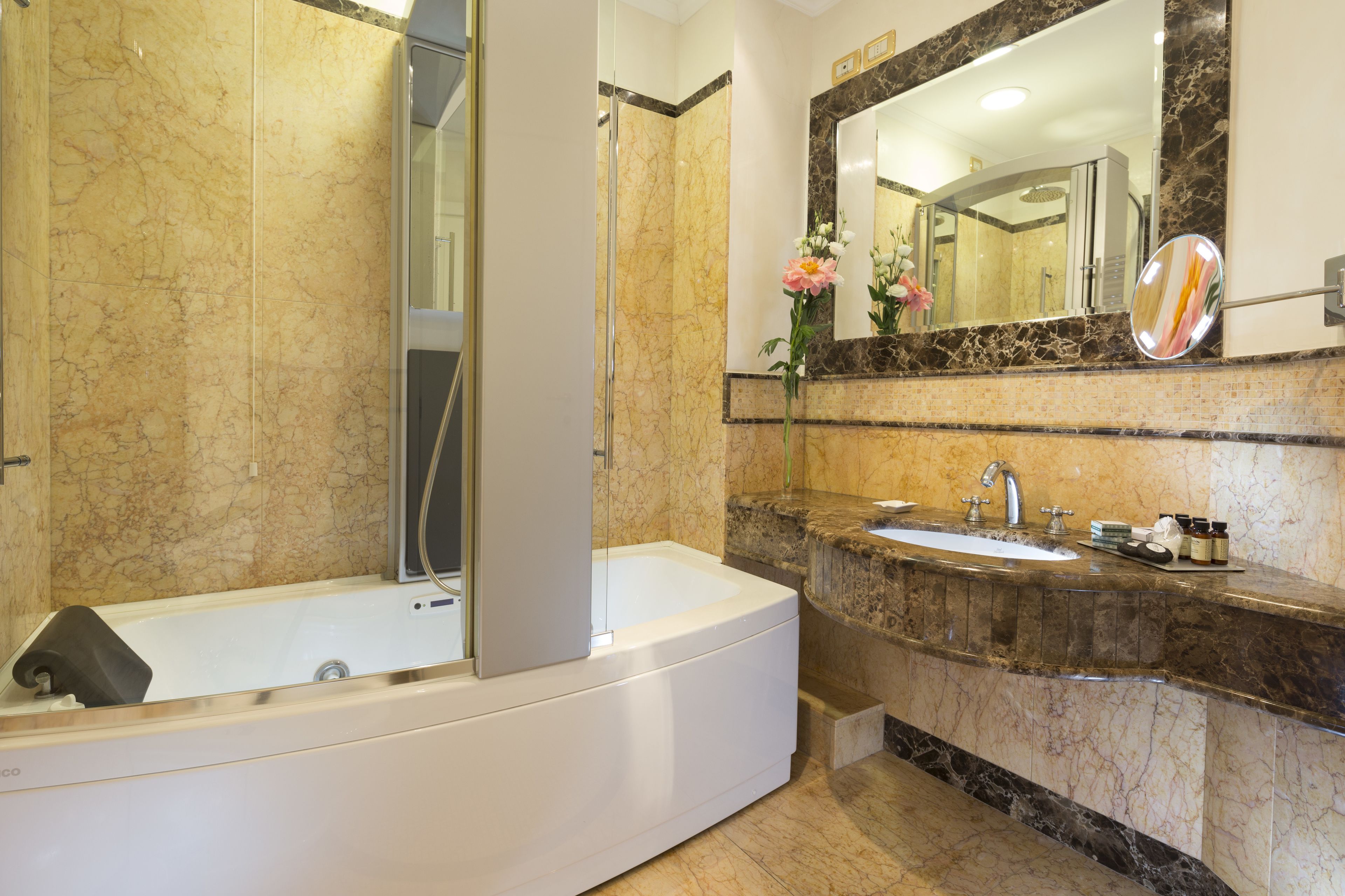 A modern bathroom with a bathtub, a large mirror, and a marble countertop.