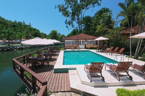 A pool area with wooden deck, lounge chairs, and umbrellas. - Pousada Corsário Paraty (Paraty)
