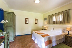 Un dormitorio con cama, mesita de noche, cómoda y ventana con cortinas.