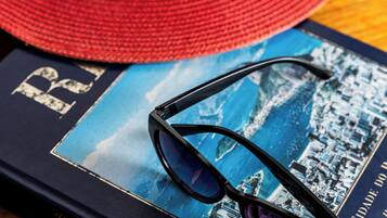 Un sombrero rojo, un par de gafas de sol y un libro con una imagen de un paisaje urbano sobre una superficie de madera.