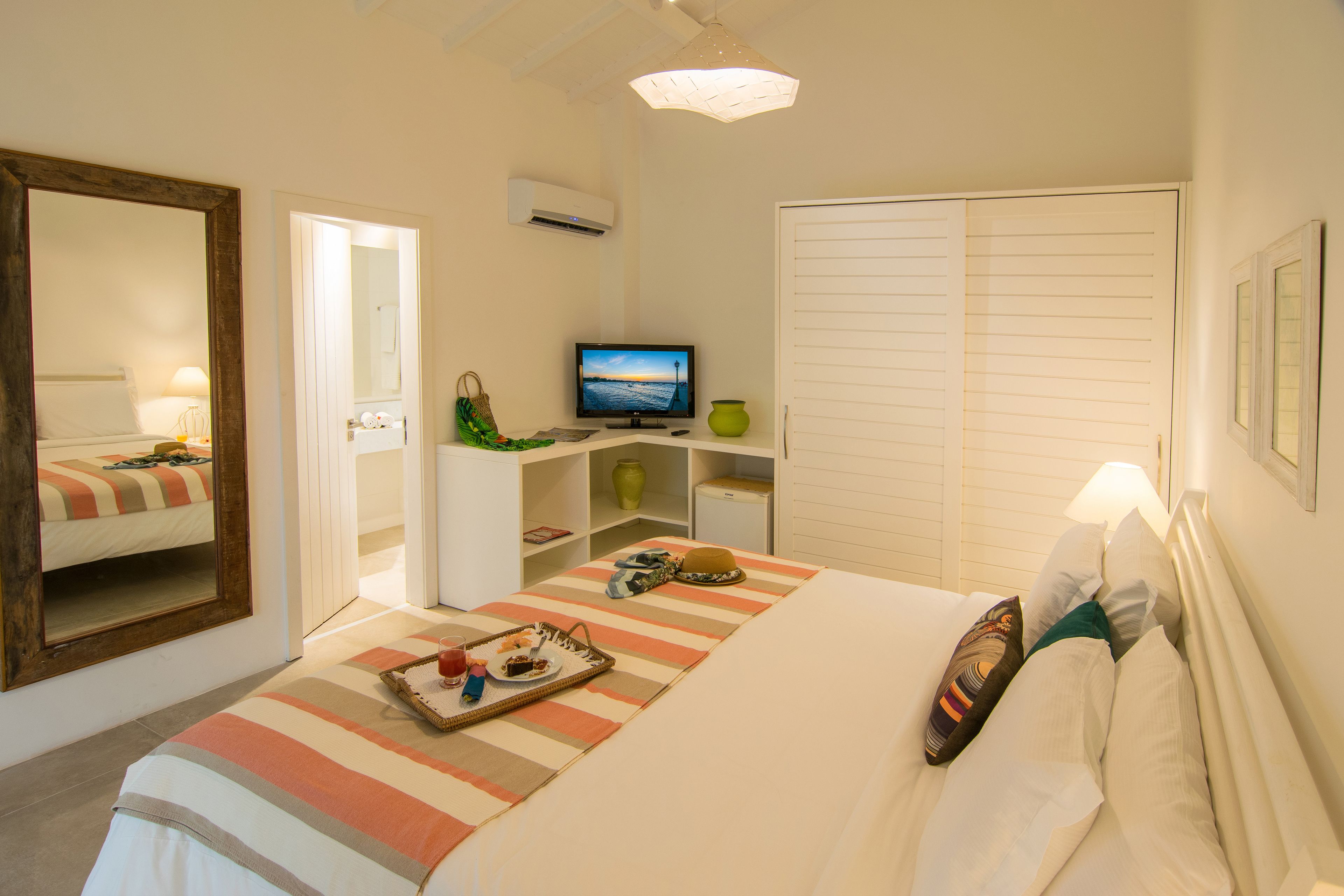 Habitació d'hotel amb llit, televisió, armari i mirall.