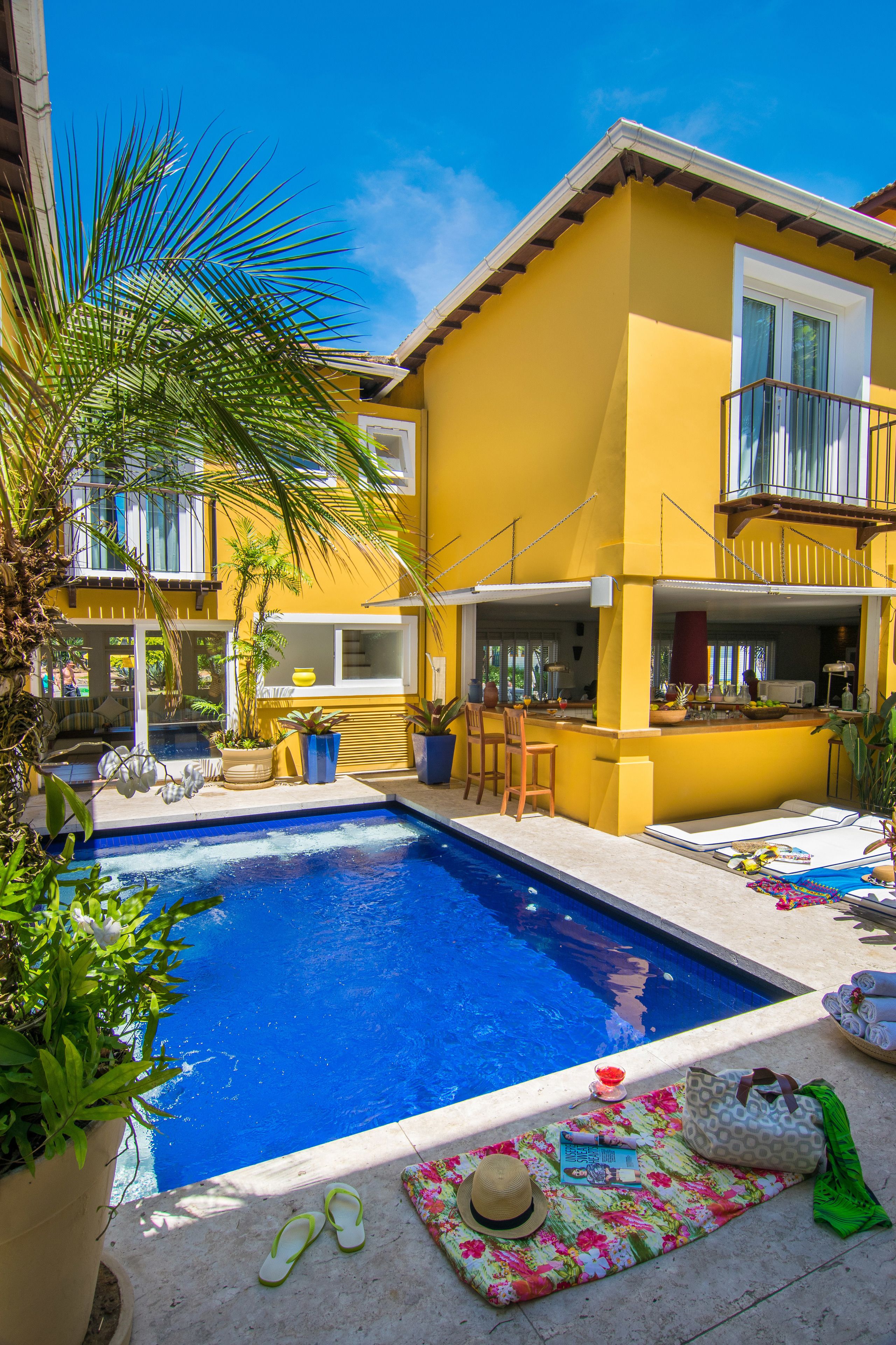 A yellow house with a swimming pool, a patio, and a bar area.