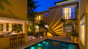 Zona de piscina con bar, asientos y una escalera que lleva a un nivel superior.